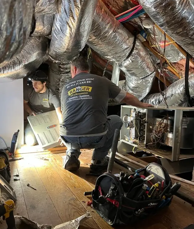 Two Ranger techs working together in an attic servicing ductwork and an air handler