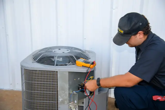 Ranger technician diagnosing an outdoor AC unit with a multimeter