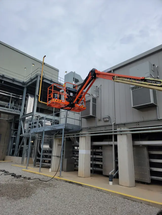 Ranger technician on boom lift servicing commercial HVAC at industrial facility